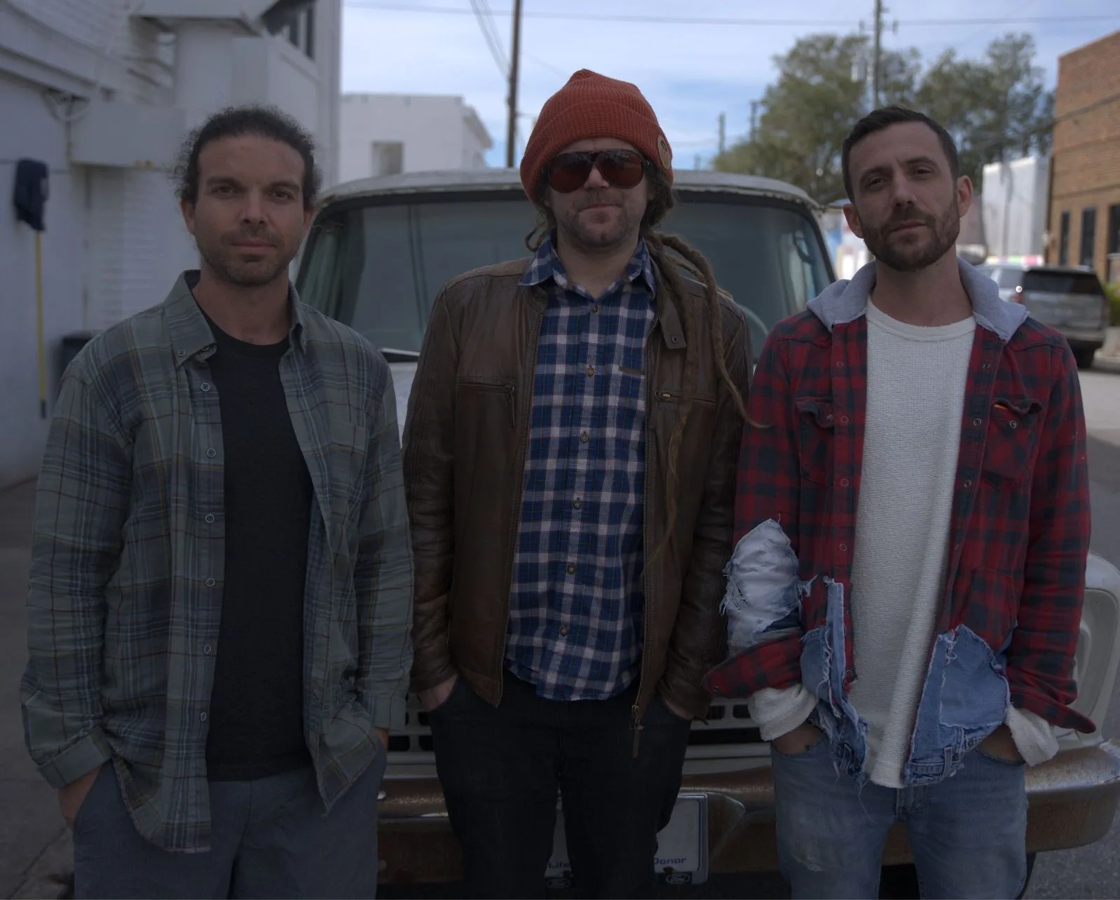 Three members of Algorhythm standing in front of a vintage pickup truck
