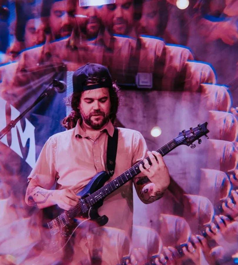 Algorhythm guitarist singing into the microphone under magenta stage lights